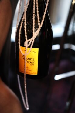 A bottle of La Grande Dame 2008 champagne adorned with a delicate pearl necklace, creating an elegant and luxurious atmosphere.