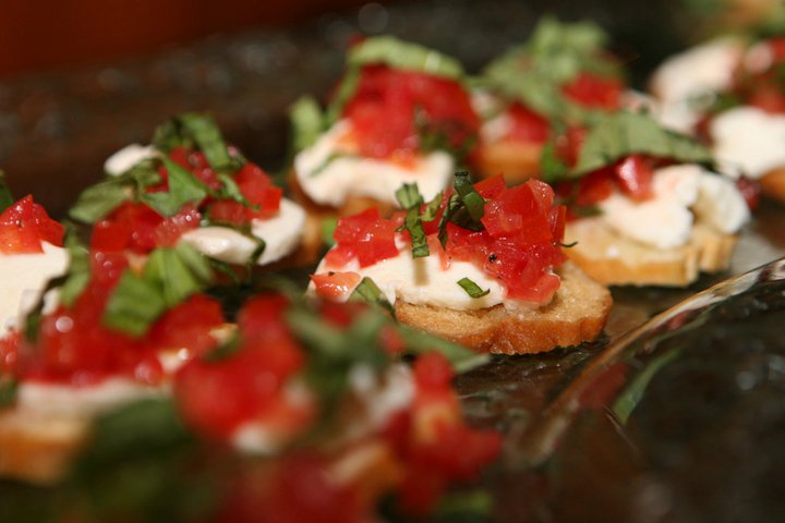 Close-up of bruschetta topped with diced tomatoes, fresh basil, and mozzarella on toasted baguette slices. The vibrant colors evoke a fresh, appetizing tone.